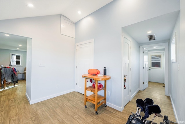 corridor featuring lofted ceiling, baseboards, visible vents, and light wood-style floors