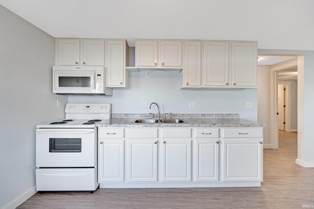 kitchen featuring white appliances, a sink, light wood-style flooring, and baseboards