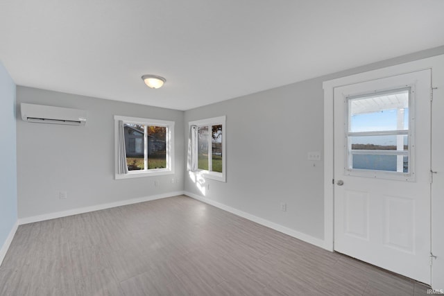 empty room featuring a wall mounted air conditioner and baseboards