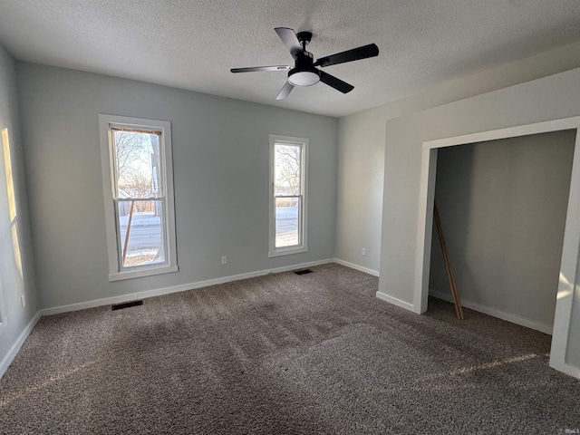 unfurnished bedroom with multiple windows, dark carpet, and visible vents