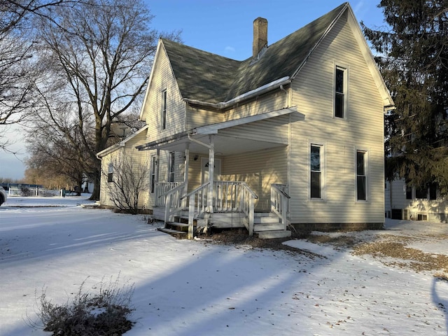 view of snow covered exterior featuring a chimney and a porch