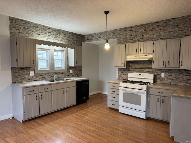 kitchen with black dishwasher, light wood-style floors, white gas stove, under cabinet range hood, and a sink