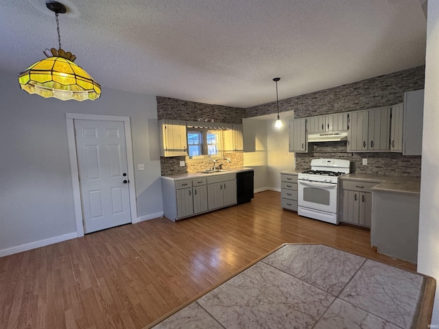 kitchen with black dishwasher, dark wood-style flooring, light countertops, white range with gas cooktop, and under cabinet range hood