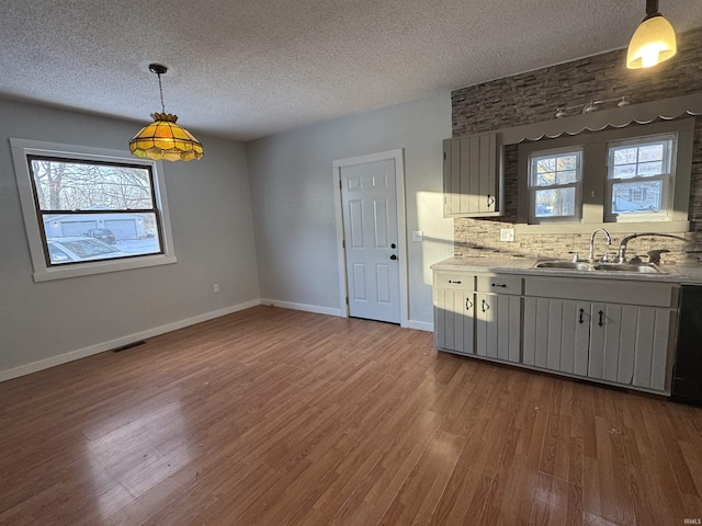 kitchen featuring dark wood-style floors, light countertops, a sink, and baseboards