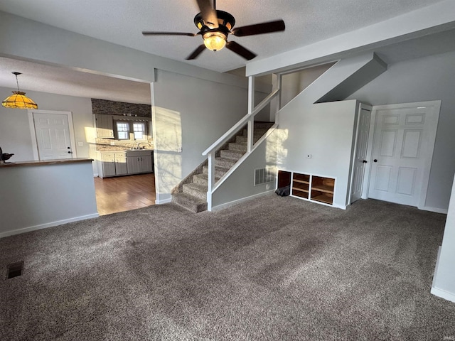 unfurnished living room featuring carpet floors, a sink, stairway, and a textured ceiling