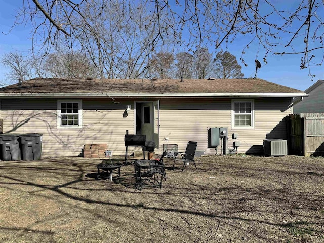 back of property with central AC, fence, and a fire pit