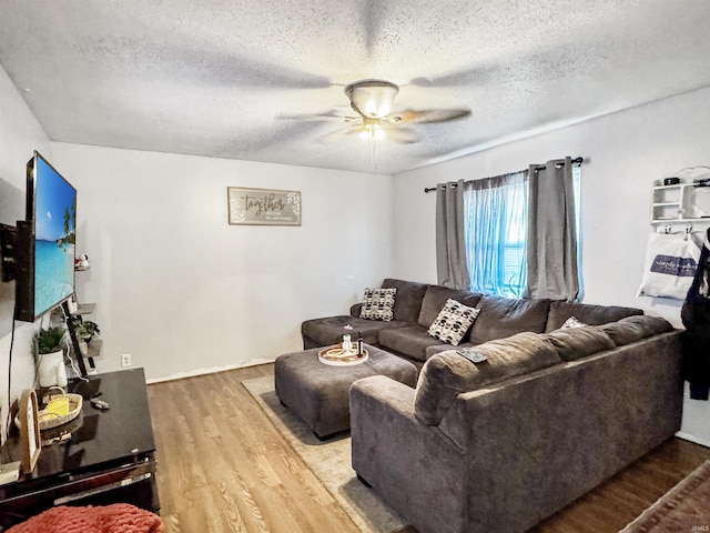 living room featuring a ceiling fan, a textured ceiling, and wood finished floors