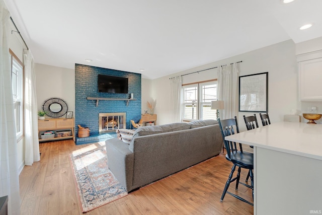 living area with light wood-style floors, recessed lighting, and a fireplace