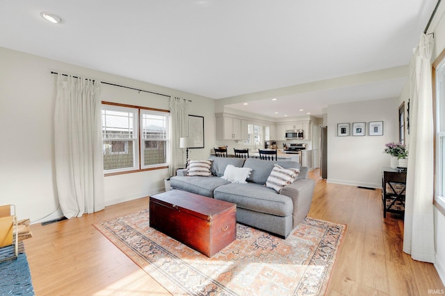 living area featuring light wood finished floors, visible vents, and baseboards