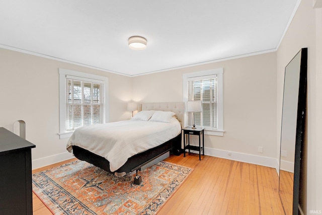 bedroom with baseboards, light wood-style flooring, and crown molding