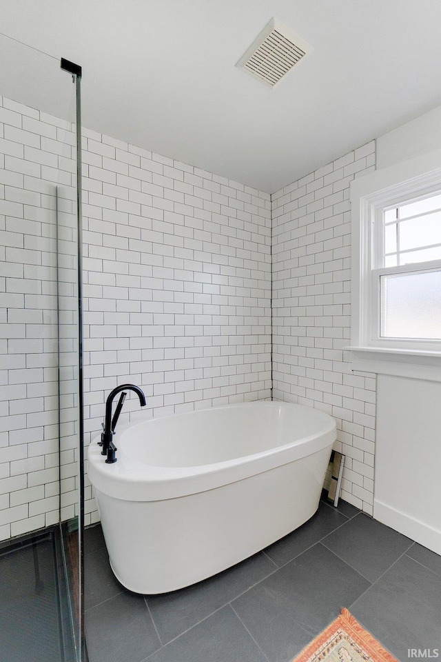 full bath with a freestanding tub, tile walls, visible vents, tile patterned floors, and a stall shower