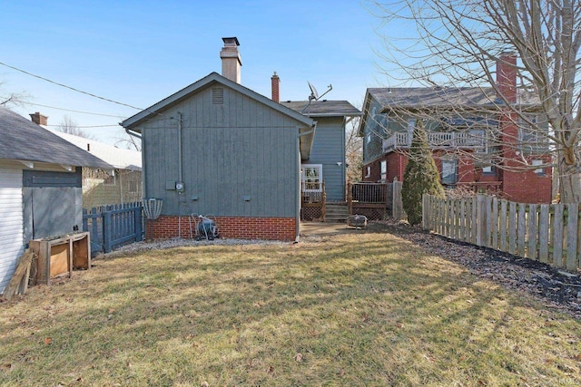 back of house with a fenced backyard, a chimney, a wooden deck, and a yard