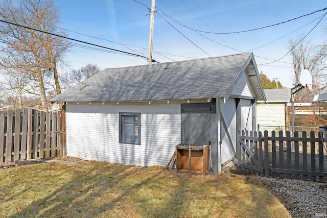 back of house with a shingled roof, a lawn, an outdoor structure, and a fenced backyard