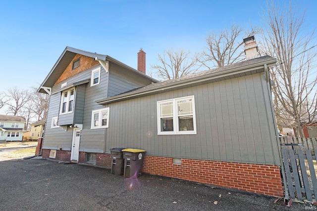 view of property exterior with crawl space and a chimney