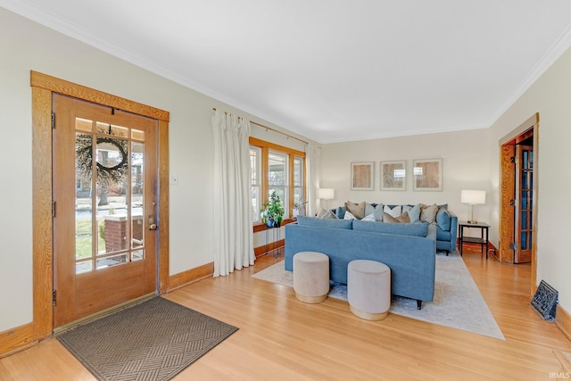 living area with ornamental molding, wood finished floors, and baseboards