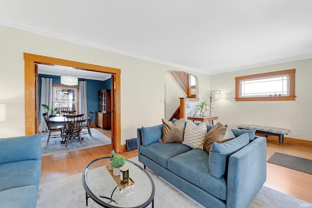 living area with baseboards, ornamental molding, a wealth of natural light, and light wood-style floors