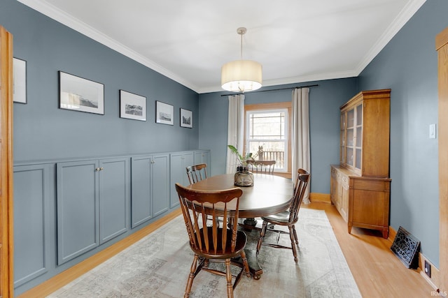 dining space featuring light wood finished floors, baseboards, and ornamental molding