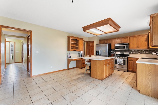 kitchen with light tile patterned floors, stainless steel appliances, decorative backsplash, a sink, and a kitchen island