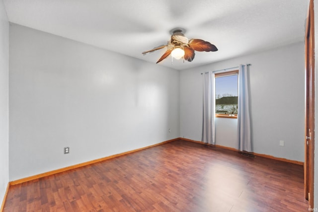 empty room with a ceiling fan, baseboards, and wood finished floors