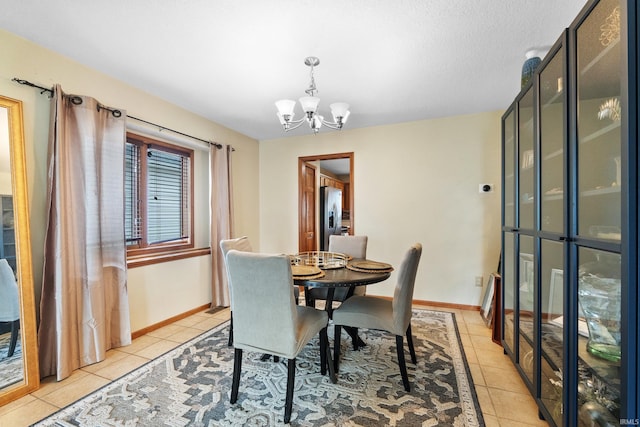 dining area with a chandelier, light tile patterned flooring, and baseboards