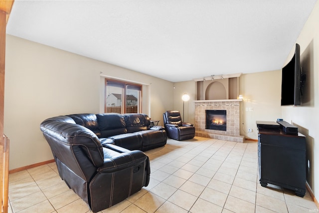 living room featuring light tile patterned floors, a glass covered fireplace, rail lighting, and baseboards