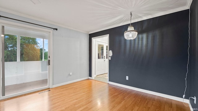 spare room with baseboards, visible vents, wood finished floors, and ornamental molding