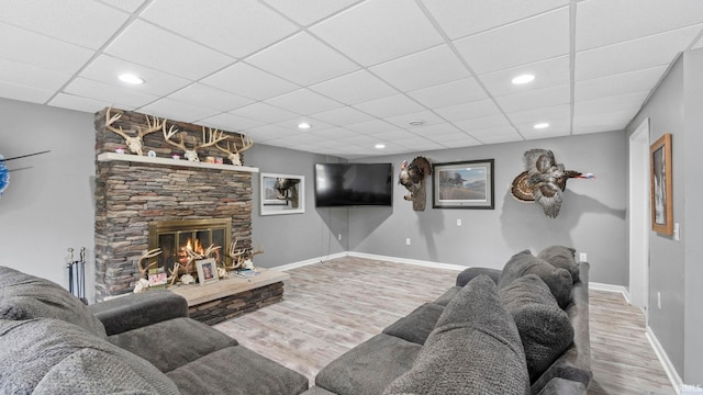 living area featuring recessed lighting, a stone fireplace, baseboards, and wood finished floors