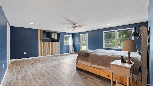 bedroom featuring access to outside, a textured ceiling, baseboards, and wood finished floors