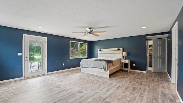 bedroom featuring access to exterior, a textured ceiling, baseboards, and wood finished floors