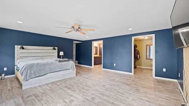 bedroom featuring ensuite bathroom, wood finished floors, a walk in closet, and baseboards