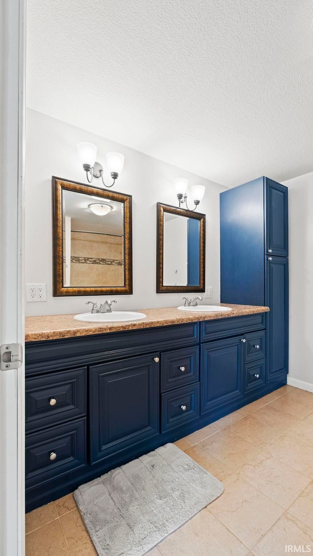 full bath with double vanity, a textured ceiling, and a sink