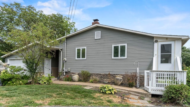 view of front of property with a garage, a front lawn, and a chimney