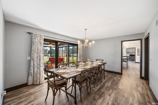 dining space featuring baseboards, a chandelier, and wood finished floors