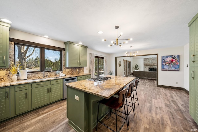 kitchen with a center island, stainless steel appliances, tasteful backsplash, green cabinets, and a sink