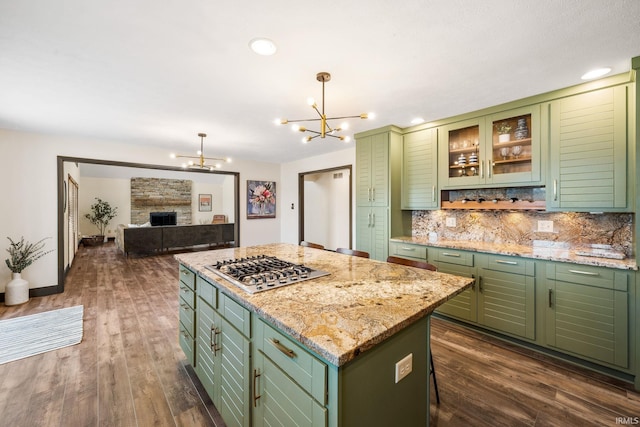 kitchen with dark wood finished floors, tasteful backsplash, stainless steel gas stovetop, a kitchen island, and green cabinetry