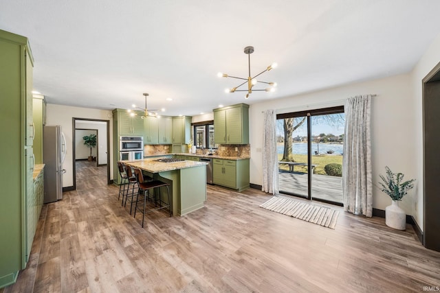 kitchen featuring a notable chandelier, backsplash, appliances with stainless steel finishes, a kitchen island, and green cabinetry