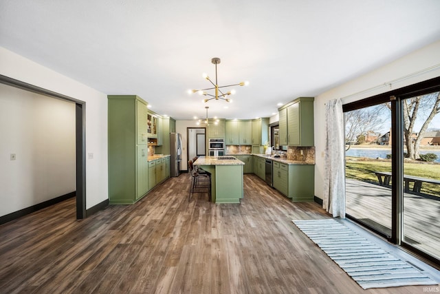 kitchen with a notable chandelier, stainless steel appliances, green cabinetry, and a kitchen breakfast bar