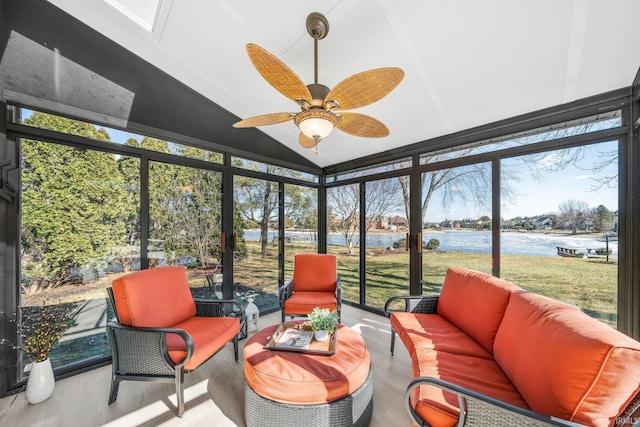 sunroom featuring a ceiling fan, a healthy amount of sunlight, vaulted ceiling, and a water view