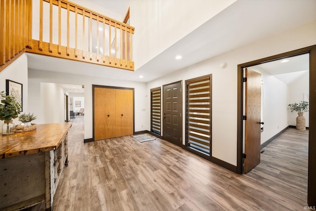 entryway with a towering ceiling, baseboards, and wood finished floors