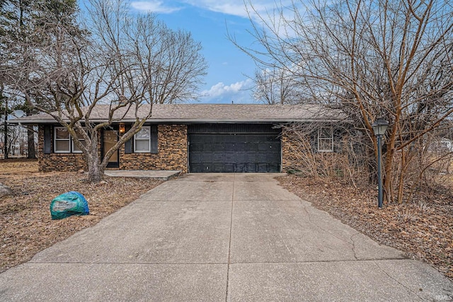 ranch-style home featuring concrete driveway, brick siding, an attached garage, and a shingled roof