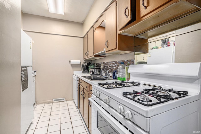 kitchen featuring white appliances, visible vents, decorative backsplash, light countertops, and a sink