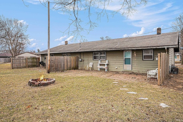 rear view of house featuring a chimney, a lawn, fence, cooling unit, and a fire pit