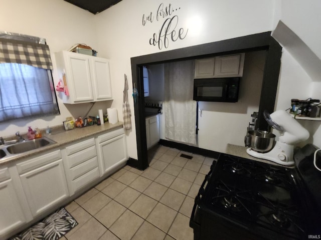 kitchen featuring light tile patterned floors, light countertops, white cabinets, a sink, and black appliances