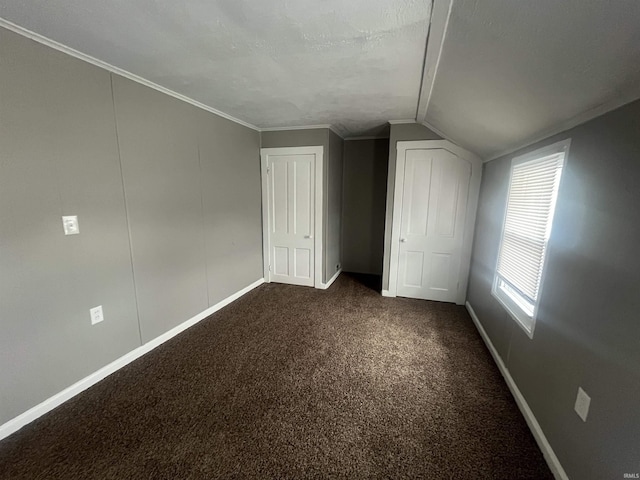 additional living space featuring baseboards, dark carpet, vaulted ceiling, and a textured ceiling