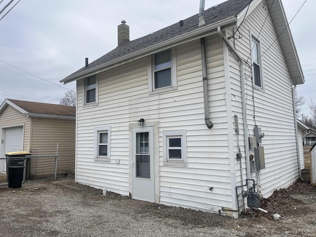 rear view of house with fence and a chimney