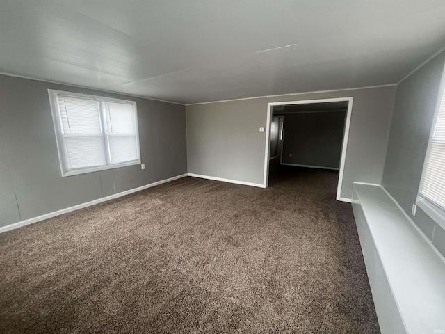 spare room featuring dark colored carpet and baseboards