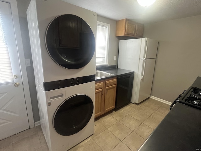 laundry room with stacked washer and clothes dryer, light tile patterned floors, a sink, laundry area, and baseboards