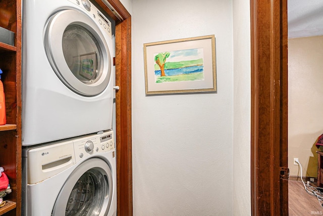 laundry area with stacked washer and dryer, laundry area, and wood finished floors