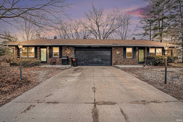 ranch-style house featuring a garage, concrete driveway, brick siding, and a chimney