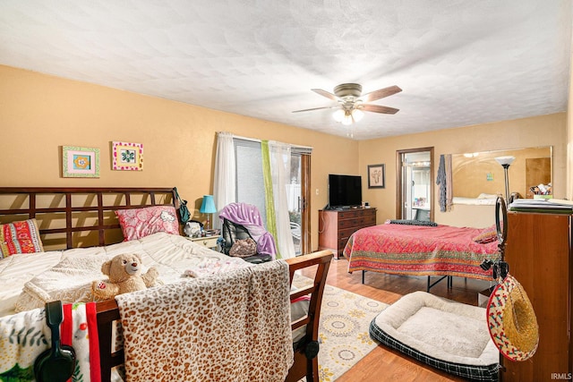 bedroom with access to exterior, ceiling fan, a textured ceiling, and wood finished floors